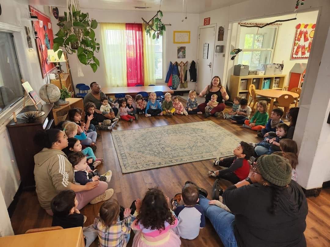 A group of children are sitting on the floor in a room.