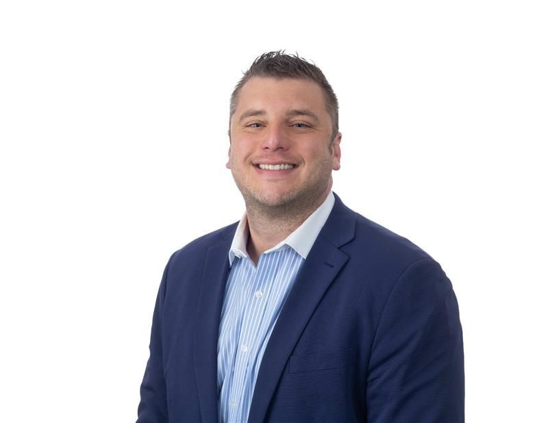 Couple reviewing documents with a professional in a living room; laptop nearby.