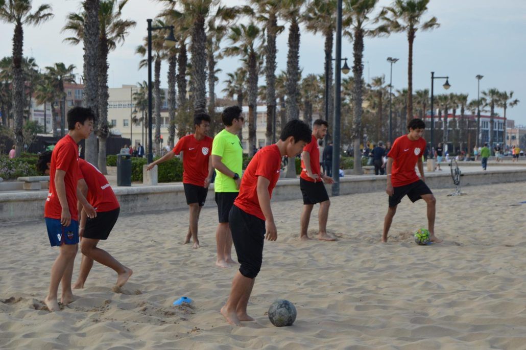 A group of young boys are playing soccer on the beach