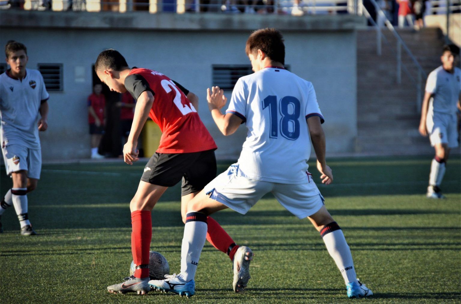 Two soccer players are playing a game of soccer on a field.