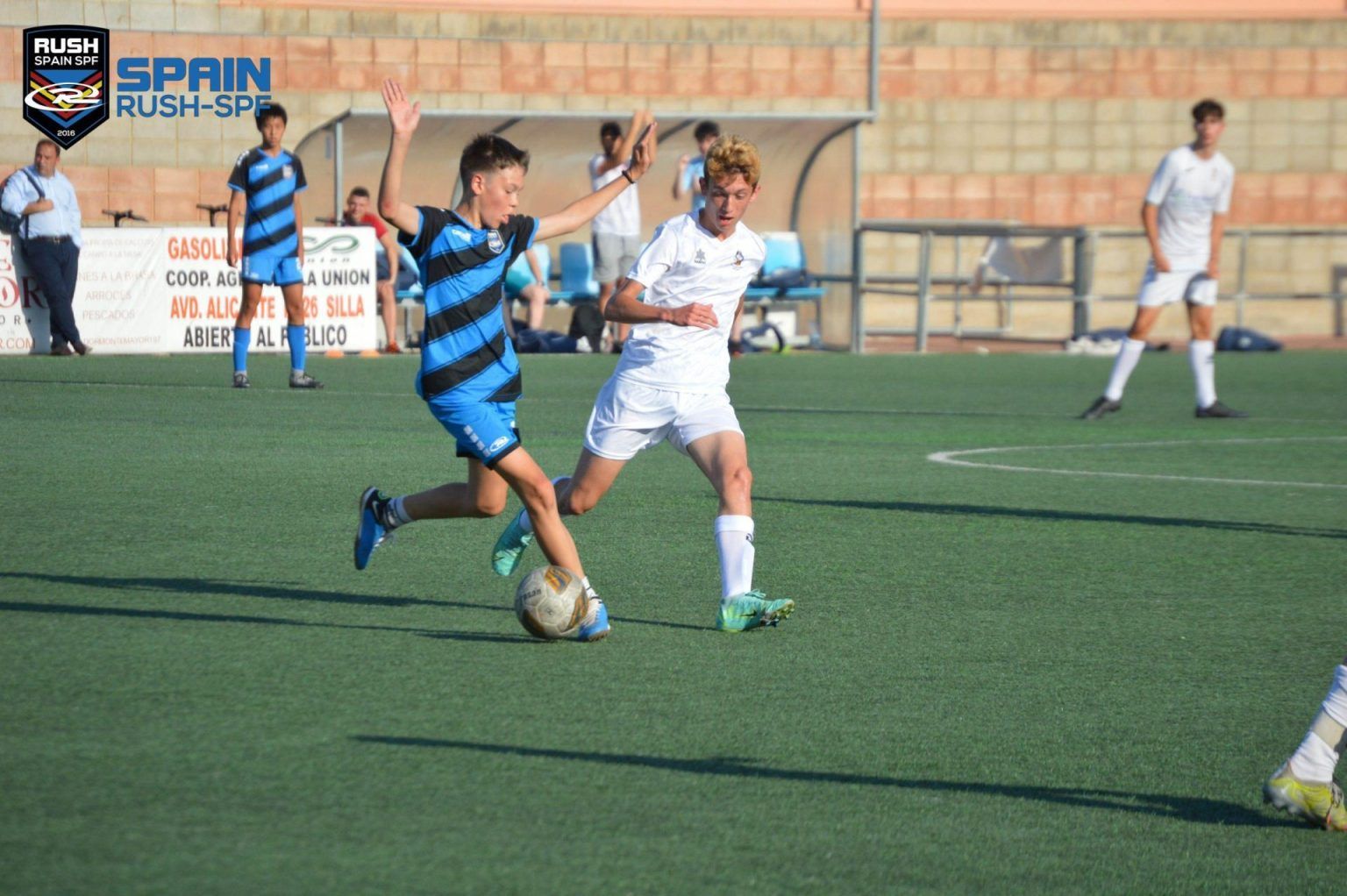 A group of Spain Rush boys are playing soccer on a field.