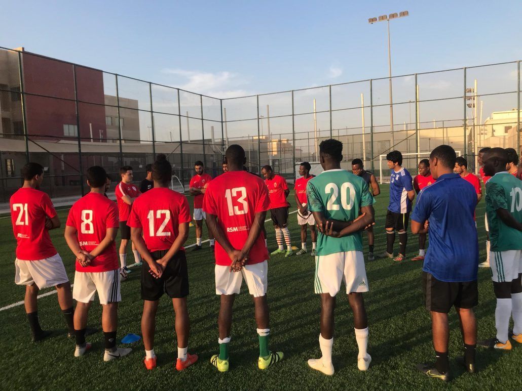 A group of soccer players are standing in a circle on a field.