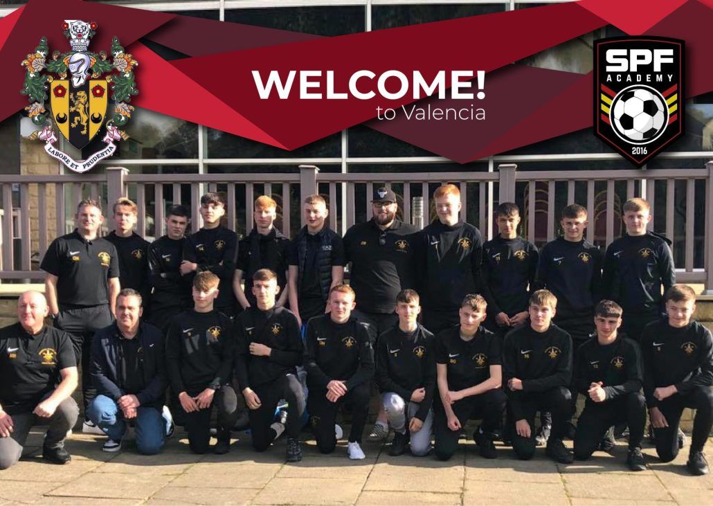 A soccer team is posing for a picture in front of a sign that says welcome to Valencia