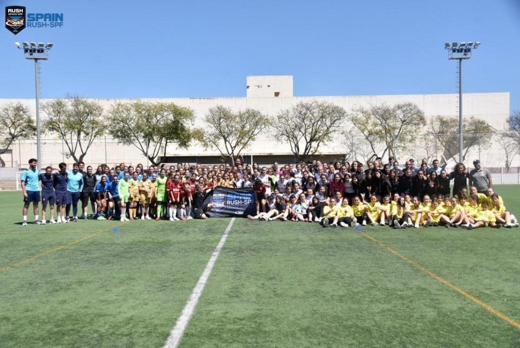 A large group of people are posing for a picture on a soccer field.