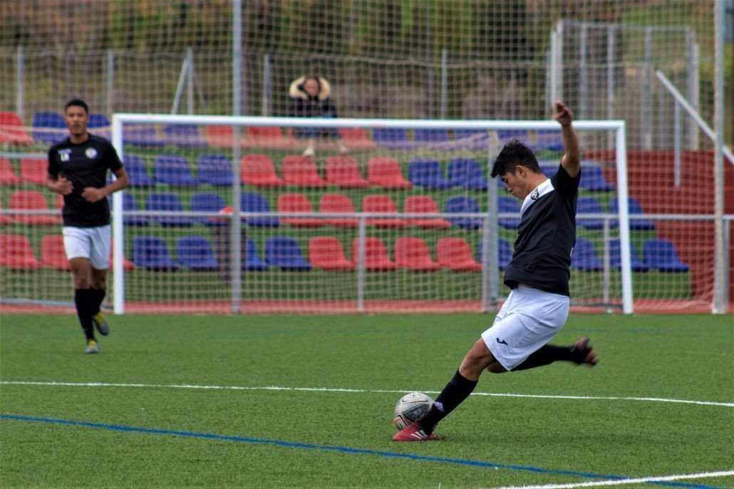 A man is kicking a soccer ball on a field.