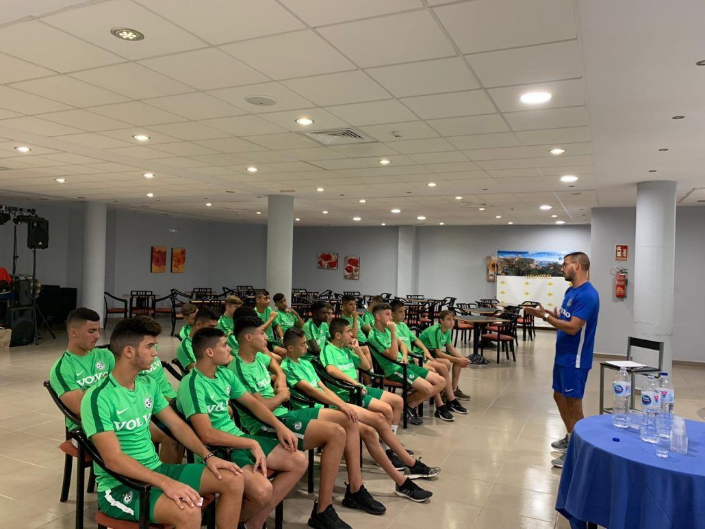 A man is giving a presentation to a group of young men sitting in chairs.