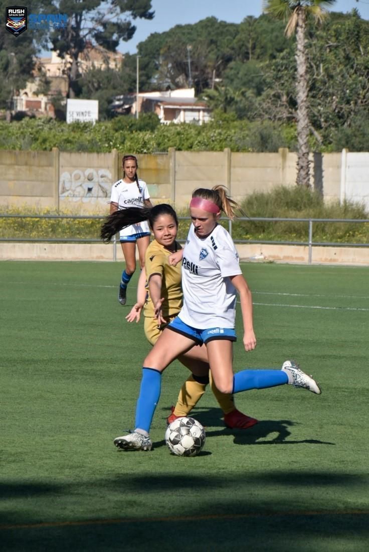 A group of young girls are playing soccer on a field.