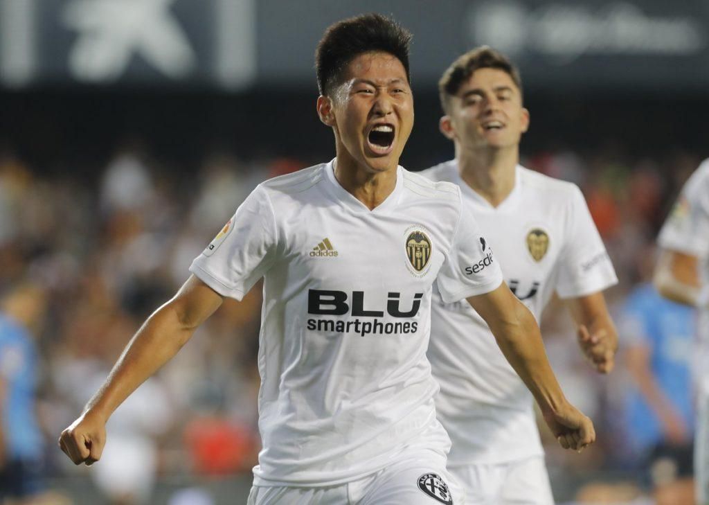 Two soccer players in white jerseys are celebrating a goal.