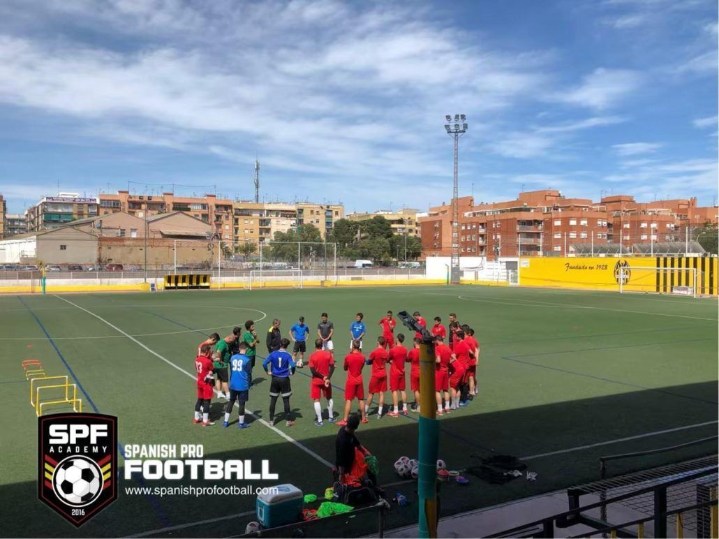 A group of people are standing on top of a soccer field.