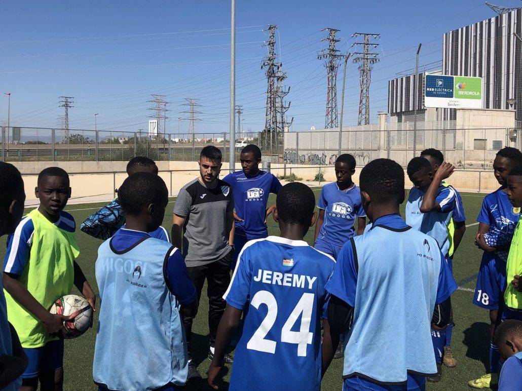 A group of soccer players are standing in a huddle on a field.