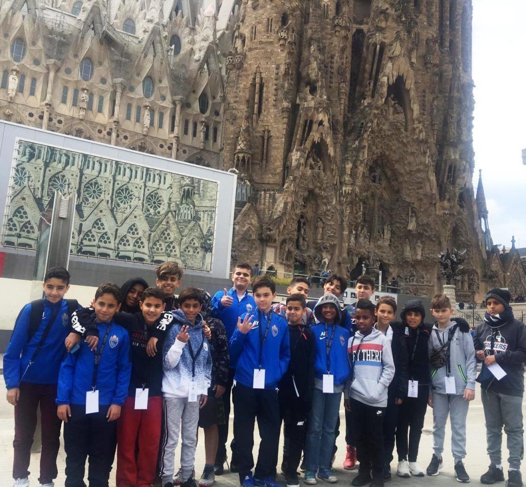 A group of children are posing for a picture in front of a large building.