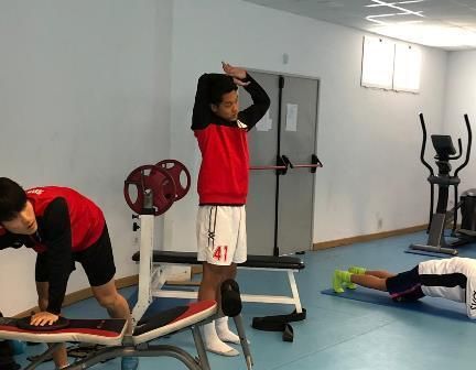 A man with the number 41 on his shorts is stretching in a gym