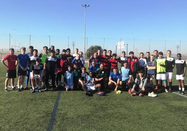 A group of young men are posing for a picture on a soccer field.