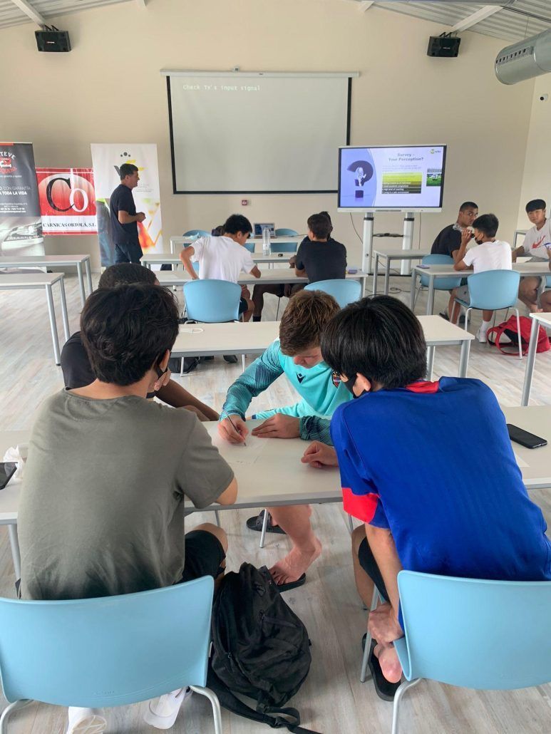 A group of young boys are sitting at tables in a classroom.