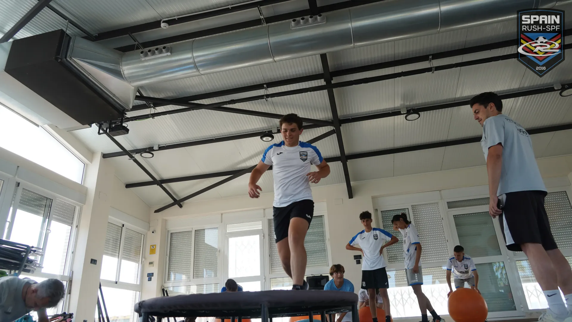 A group of young men are jumping on a trampoline in a gym.