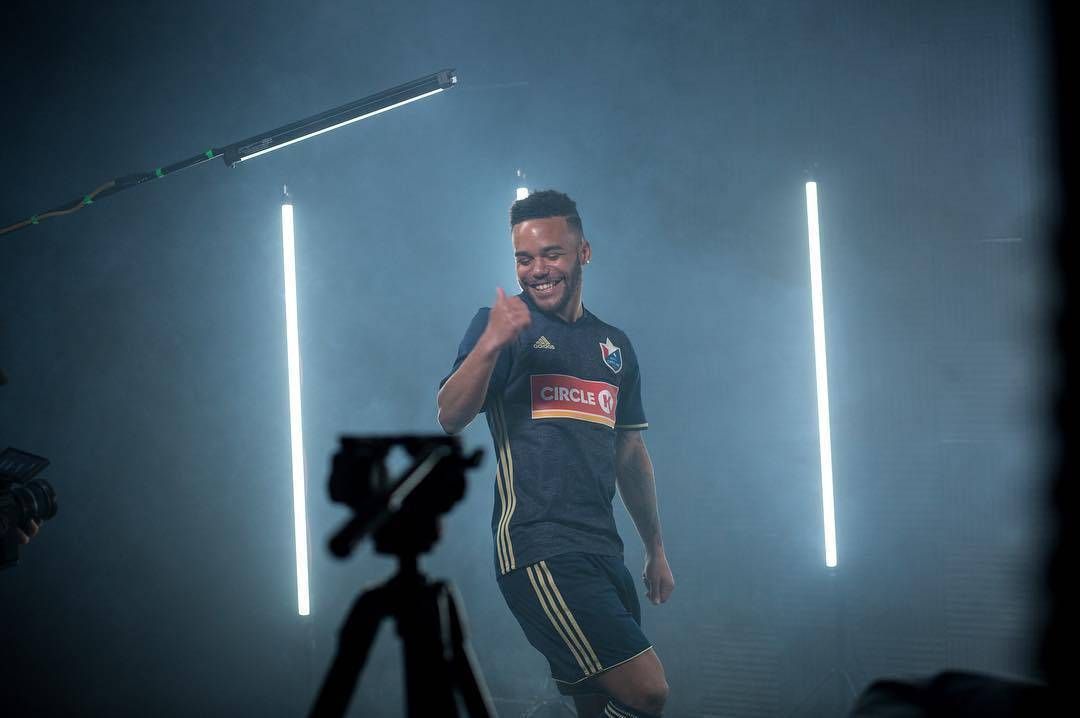 DJ Taylor in a North Carolina soccer uniform is standing in front of a camera.