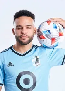 DJ Taylor in a blue Minnesota FC jersey is holding a soccer ball.