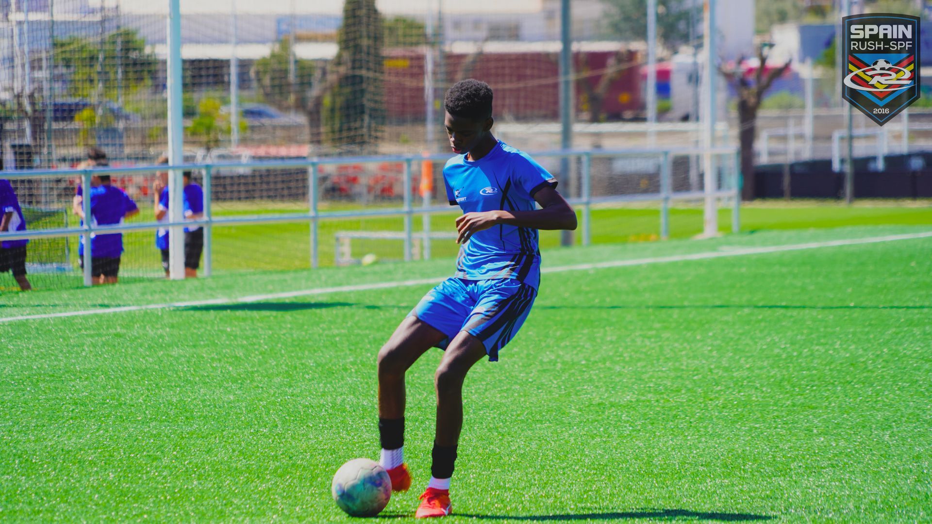 A young man is kicking a soccer ball on a field.