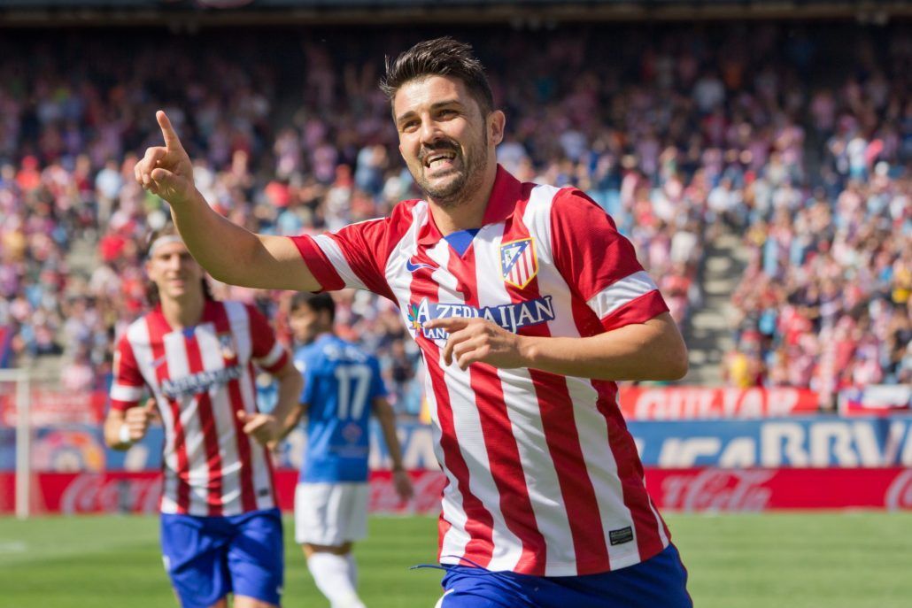 A soccer player in a red and white striped shirt is giving a thumbs up.