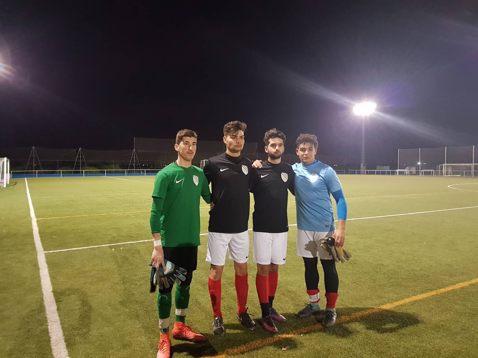 A group of young men are posing for a picture on a soccer field at night.