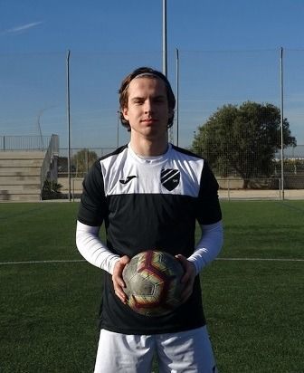 A young man is holding a soccer ball on a field.