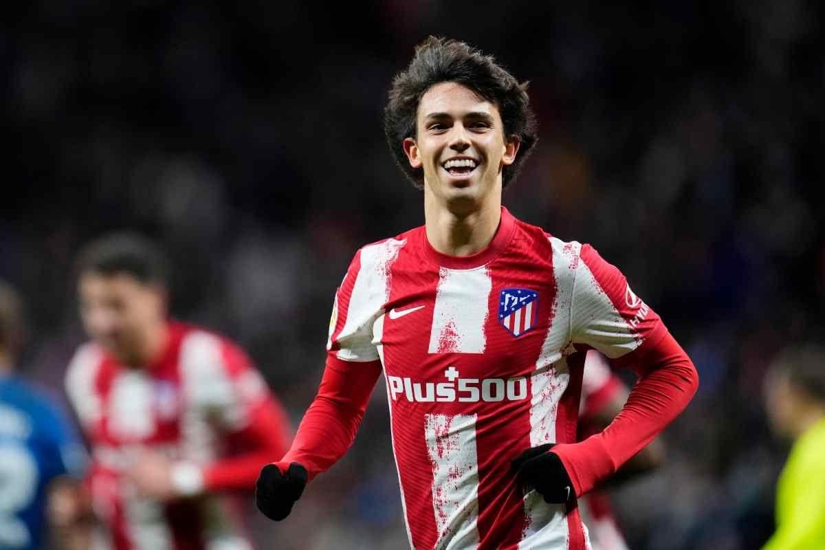 Joao Felix in a red and white jersey is smiling on the field.