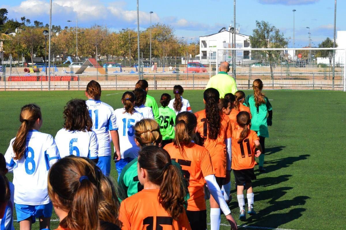 A group of young girls are walking on a soccer field.