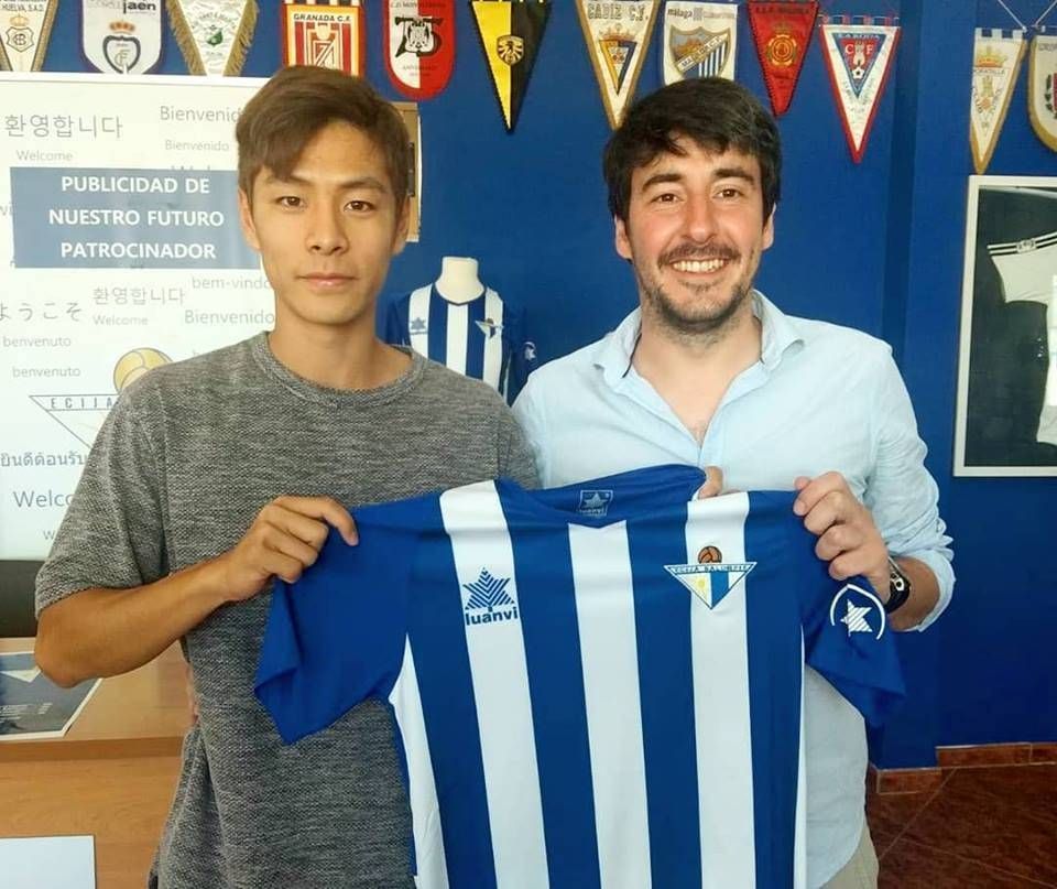 Kim Taehum posing with another man holding up his new jersey for Ecija Balompie