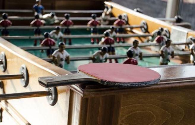 A ping pong paddle is sitting on top of a foosball table