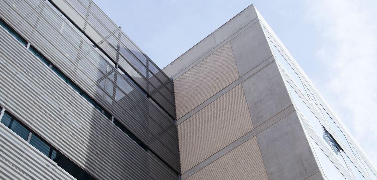 A large building with a lot of windows and a blue sky in the background.