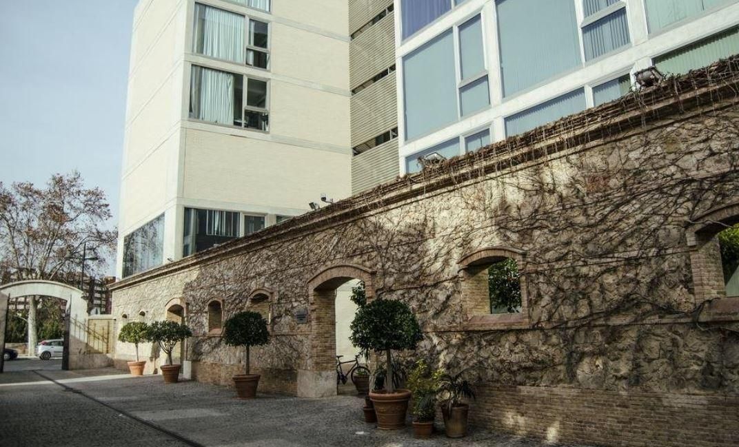 A building with a stone wall and potted plants in front of it.