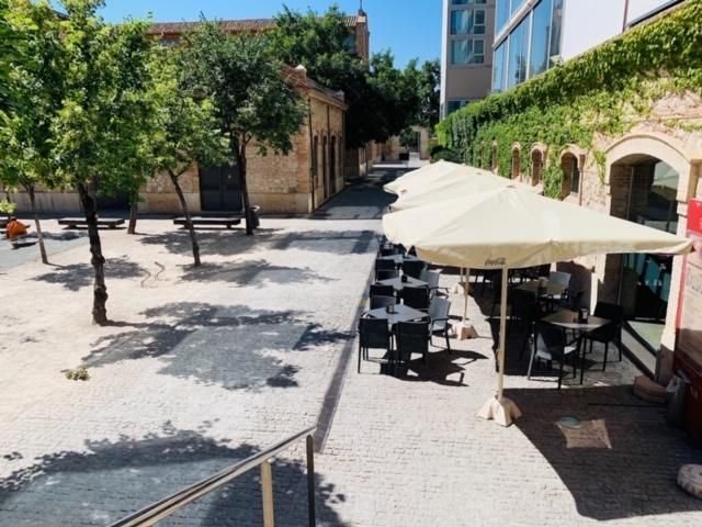 A row of tables and chairs under umbrellas in a courtyard