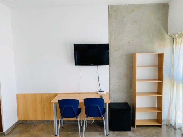 A room with a table and chairs and a flat screen tv on the wall