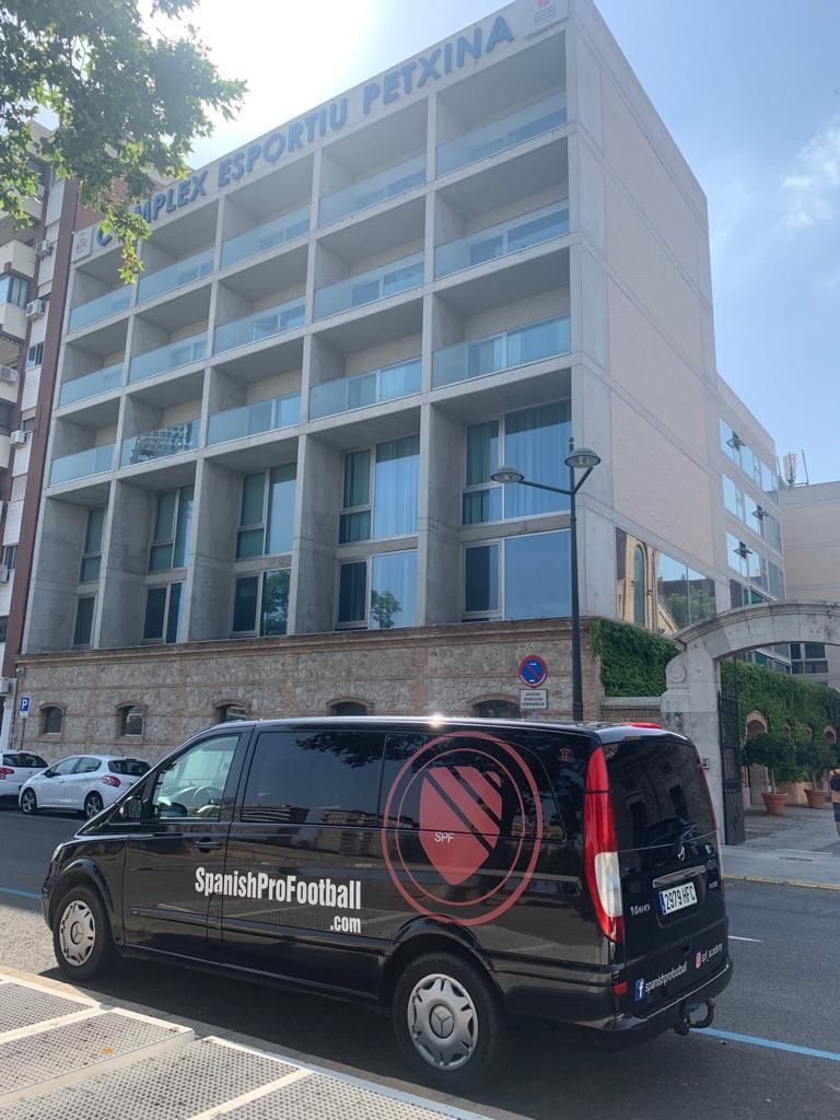 A black van is parked in front of a large building.