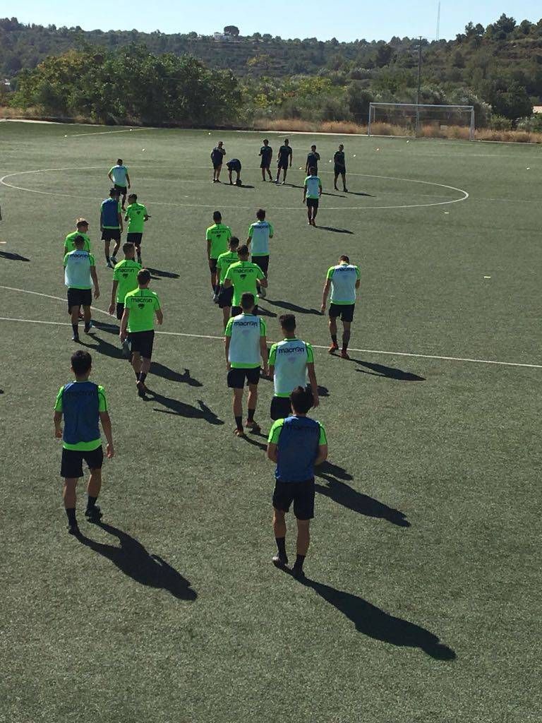 A group of people are running on a soccer field.