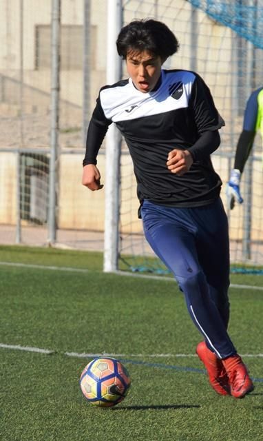 Ren Nagamatsu is kicking a soccer ball on a field.