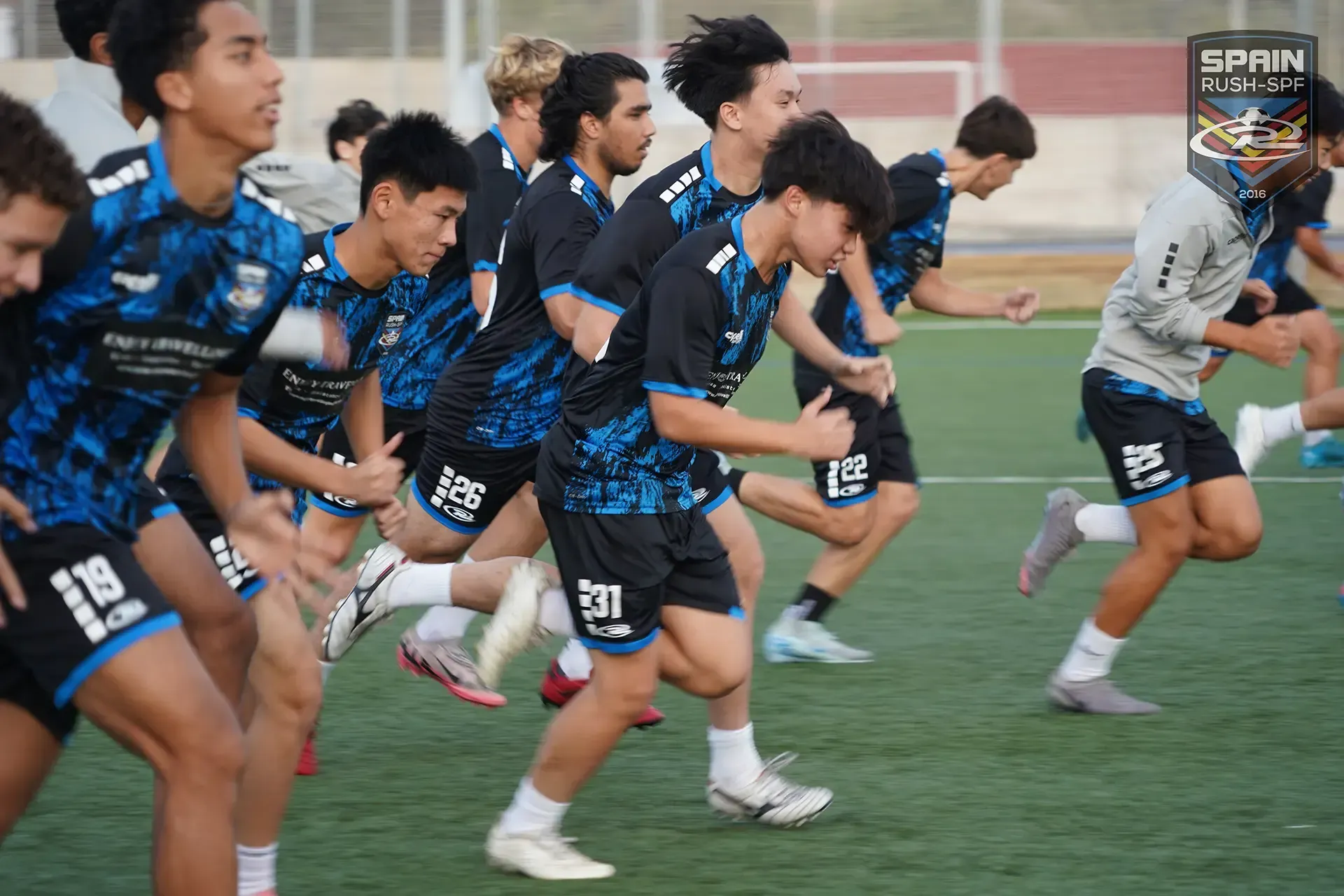 A group of young men are running on a soccer field.
