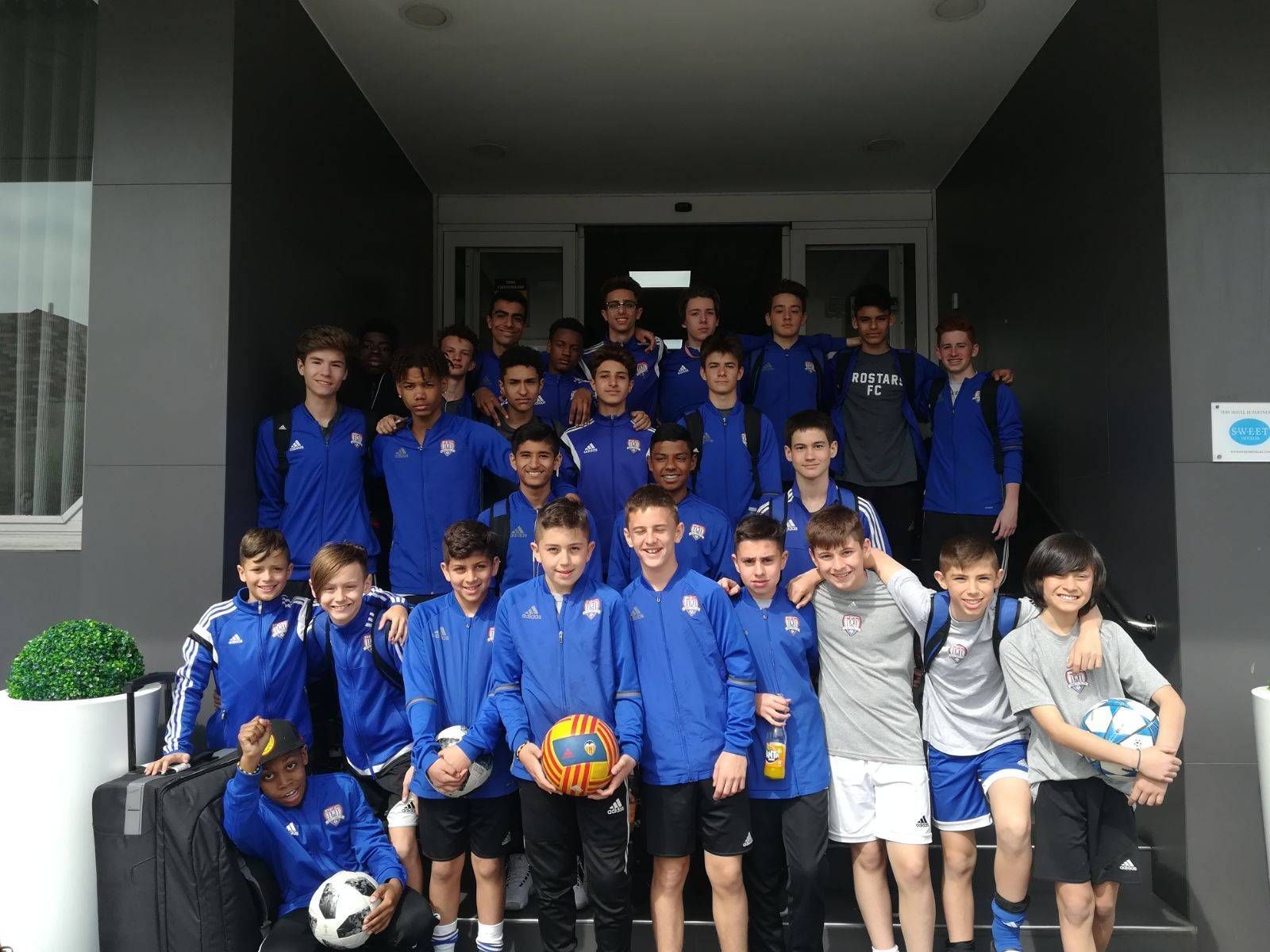 A group of young boys are posing for a picture in front of a building.