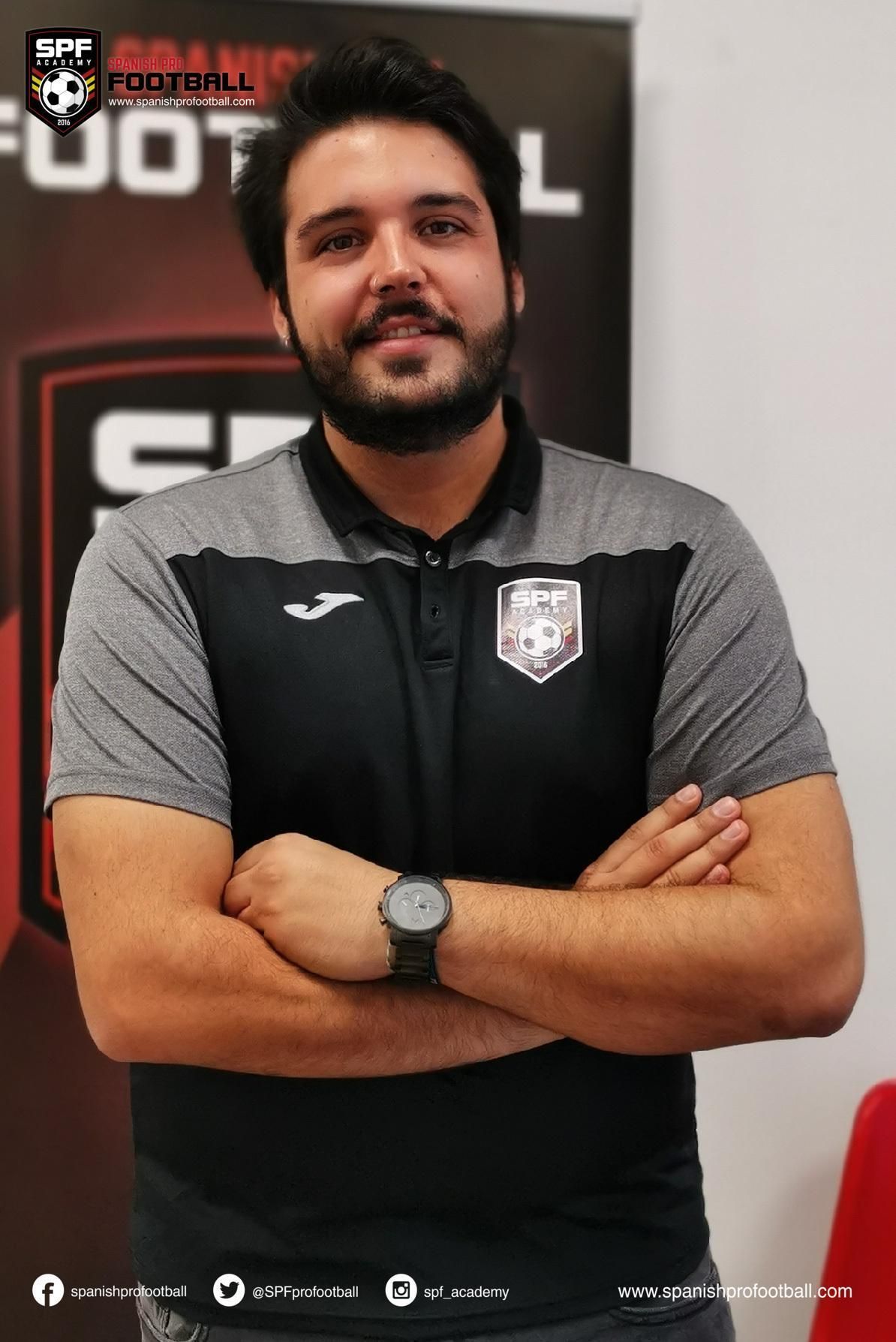 Ramon Cuello with a beard is standing with his arms crossed and wearing a watch.