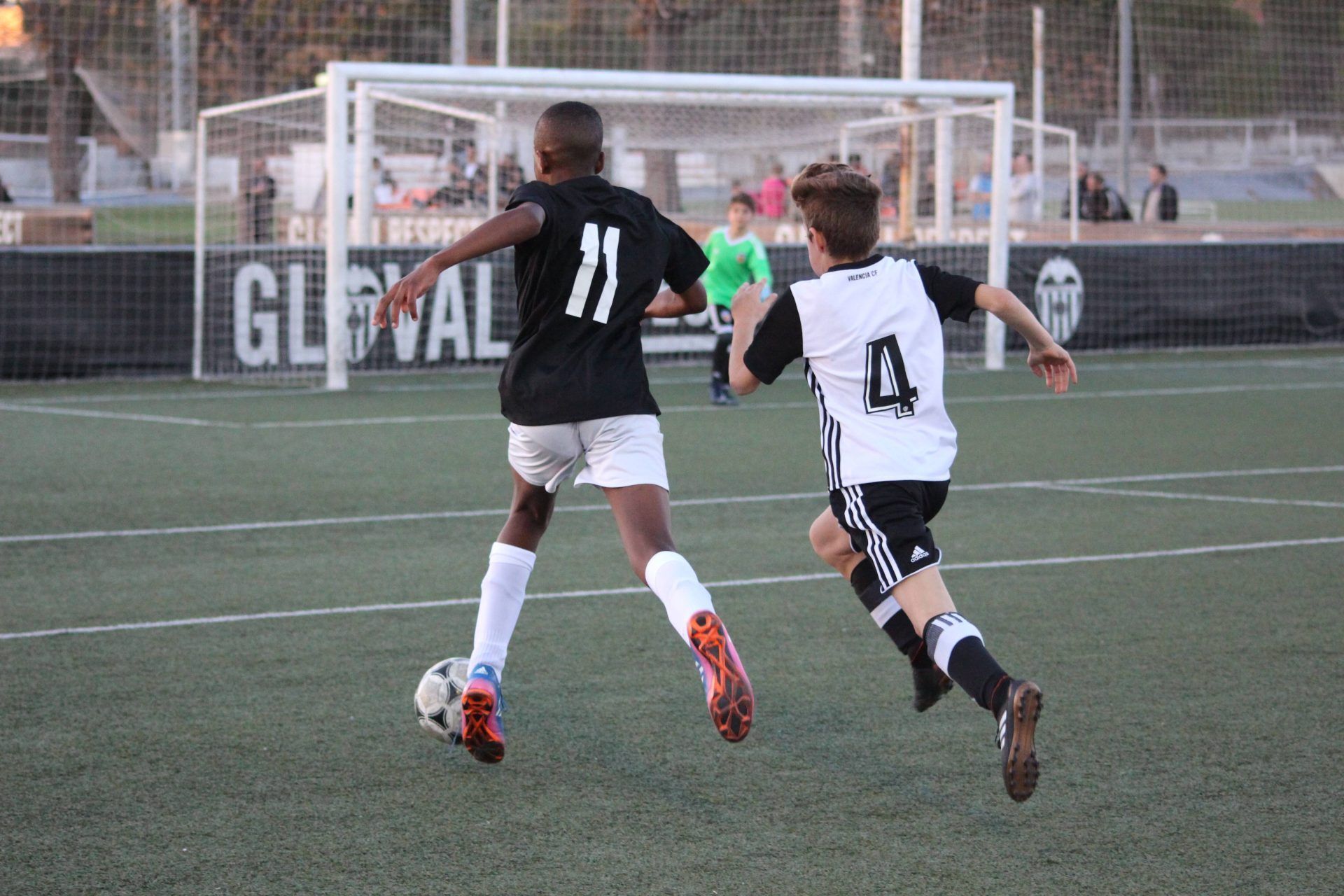 Two young boys are playing soccer on a field.