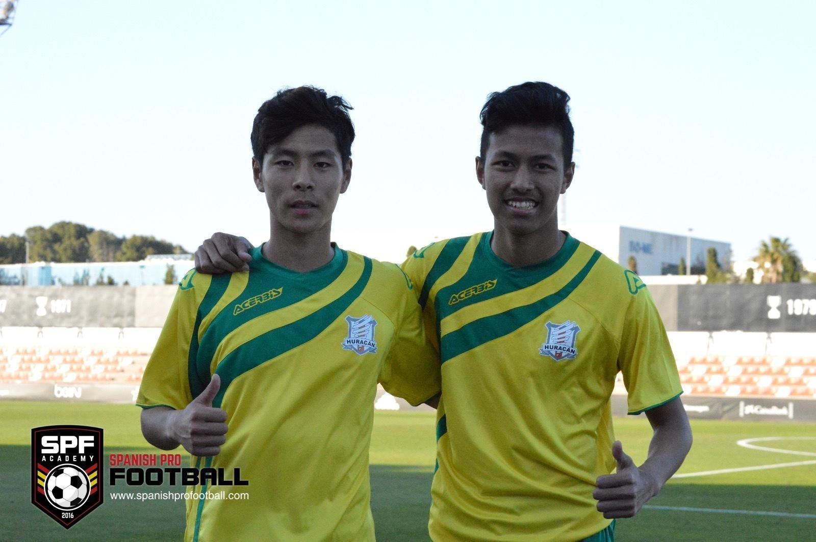 Two young men are posing for a picture on a soccer field.