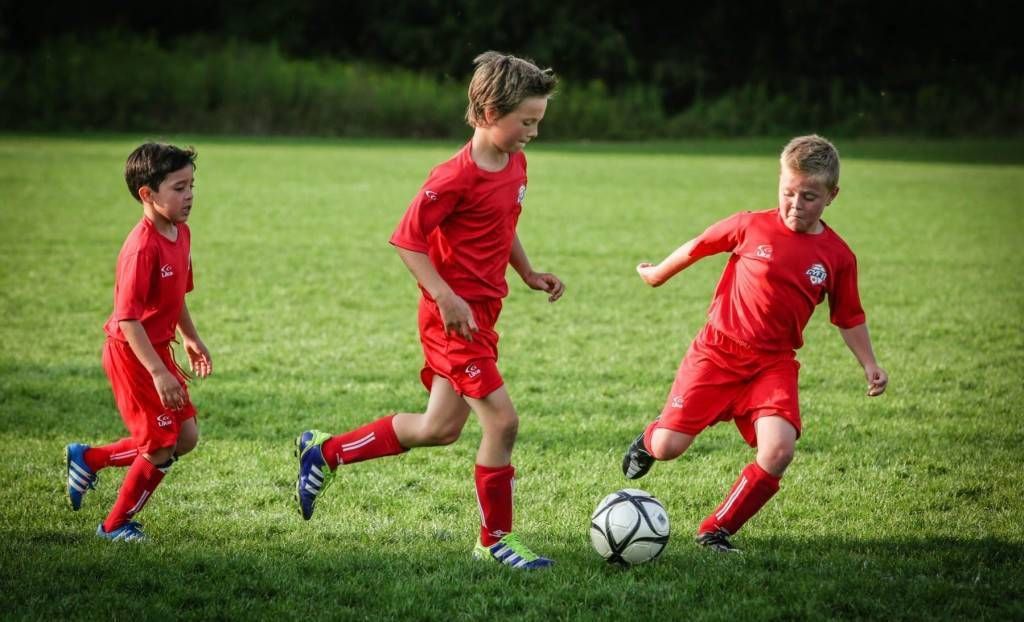 Three young boys are playing soccer on a field.