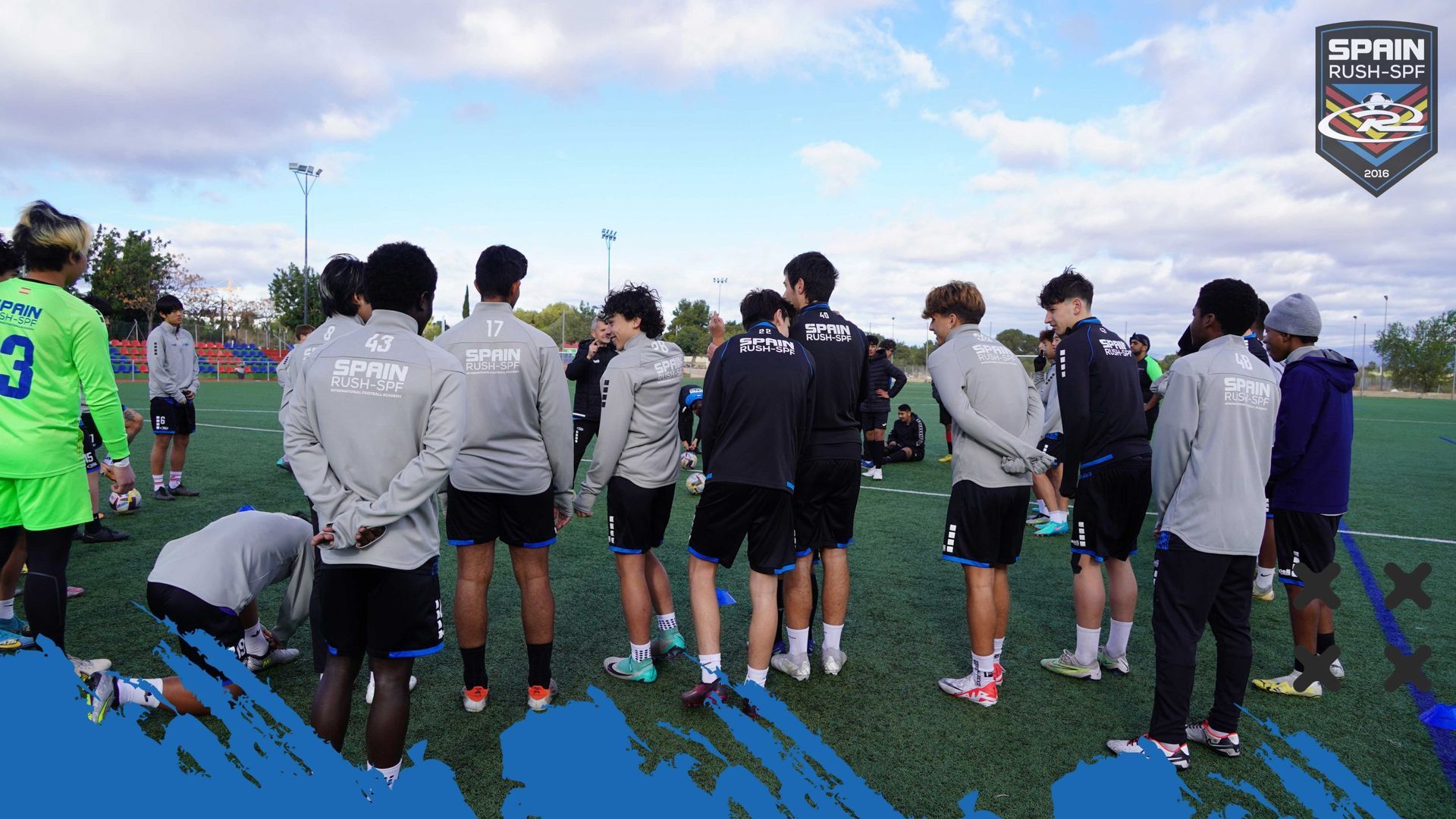 A group of soccer players are standing in a huddle on a field.