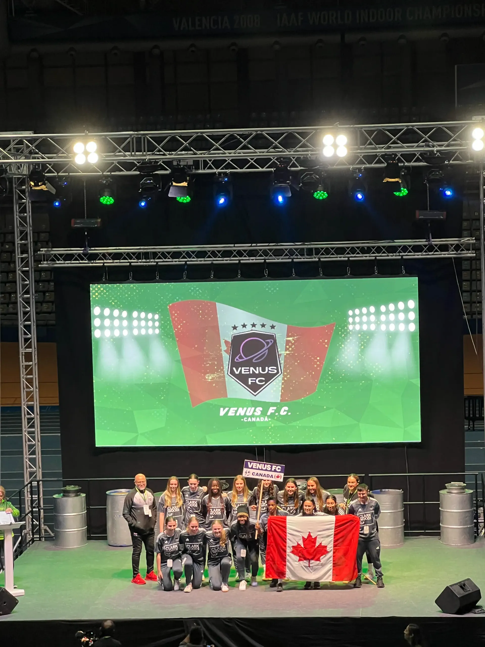 A group of people are standing on a stage in front of a large screen.