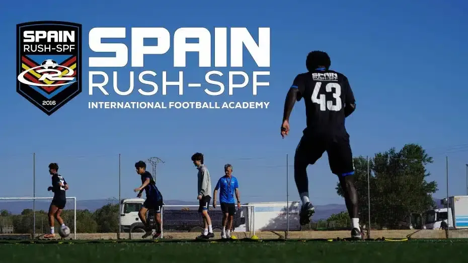 A group of boys are playing soccer on a field sponsored by Spain Rush-SPF