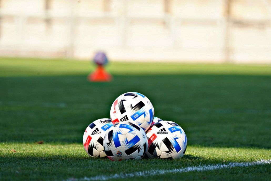 Soccer balls are stacked on top of each other on a field.