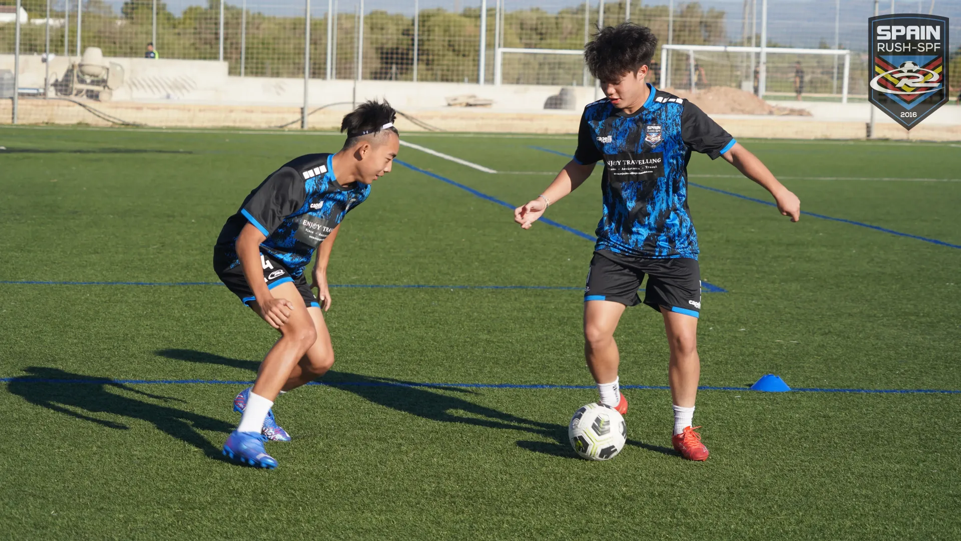 Two young men are playing soccer on a field.