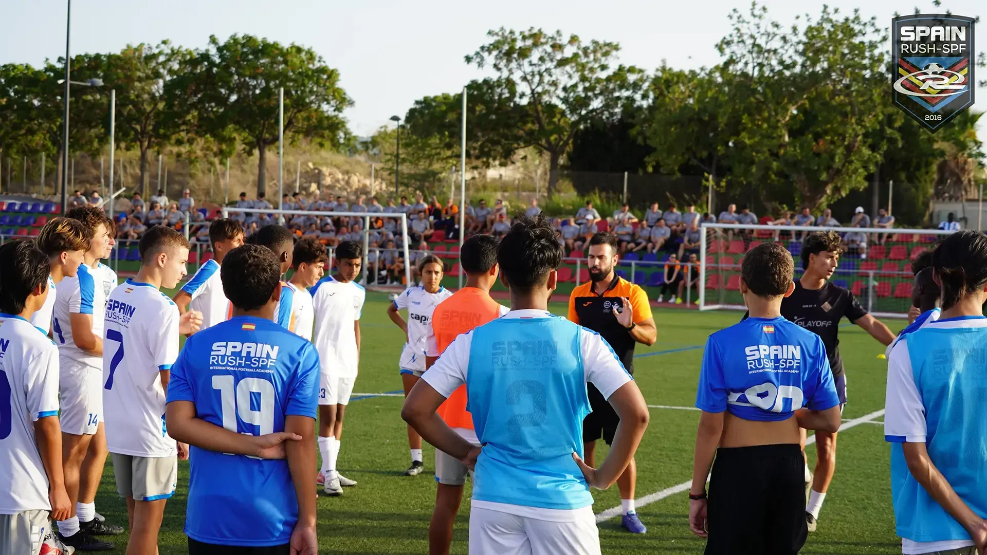 A group of soccer players are standing on a field talking to each other.