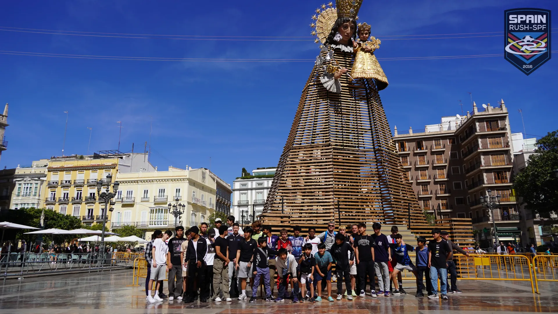 A group of people are posing for a picture in front of a large sculpture made of wood.