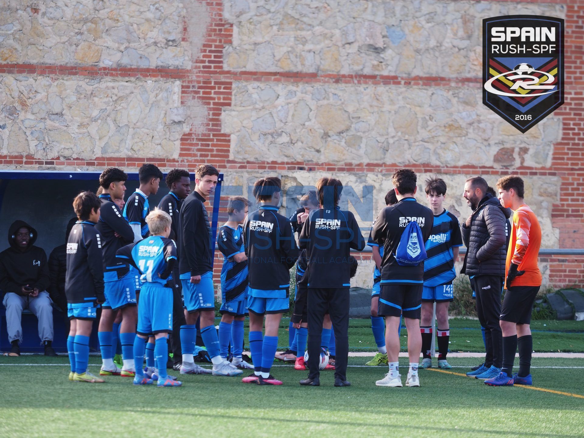 A group of soccer players are standing in a huddle on a field sponsored by spain